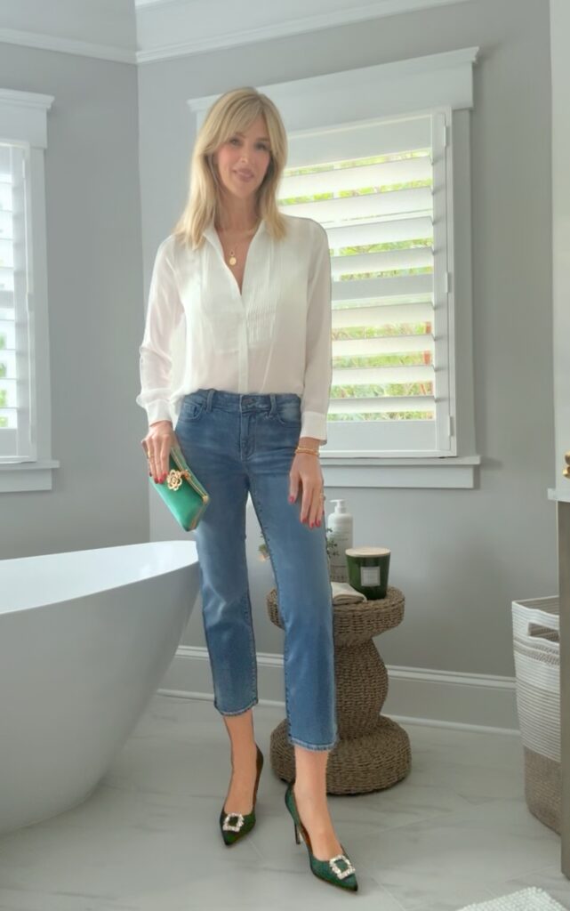 woman wearing a white button down with ankle jeans and a green clutch and a green pump to add interest to this classic style outfit